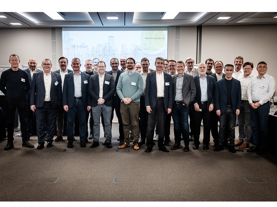 Gruppenbild der Mitglieder - 25 Personen vor einer Beamerwand