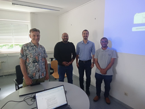 4 Personen stehen an einem Tisch nebeneinander