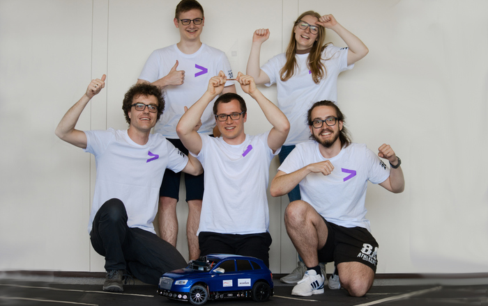Gruppenbild der jubelnden Teammitglieder, die in München dabei waren, mit Auto