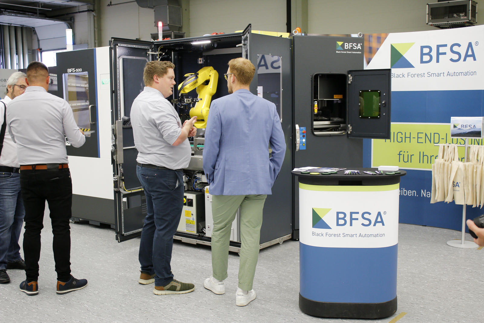 Vier Männer stehen vor einem geöffneten Industrieroboter