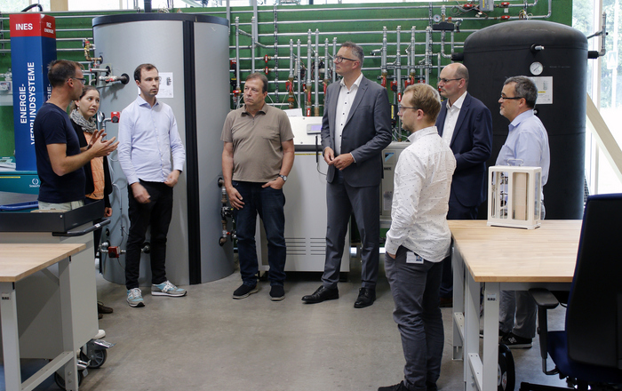  Die Besuchergruppe steht bei der Führung vor einer Heizungsanlage im RIZ Energie