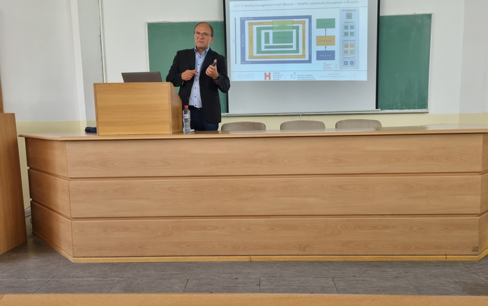 1 Person am Rednerpult vor einer Leinwand