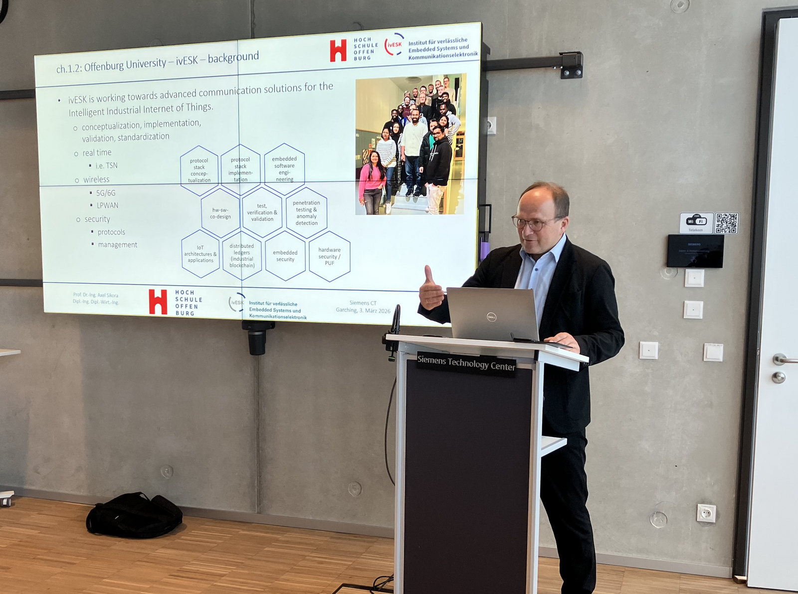 1 PErson am Rednerpult vor einer Prästationswand