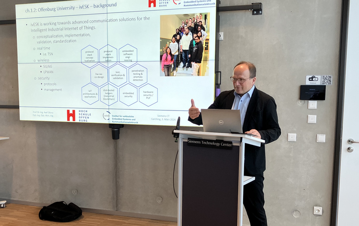 1 PErson am Rednerpult vor einer Prästationswand