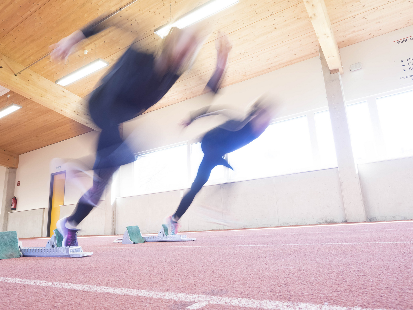 Zwei Sprinterinnen beim Start aus den Startblöcken mit Bewegungsunschärfe