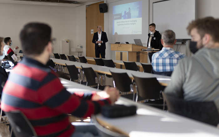 ektor Prof. Dr. Stephan Trahasch (links), Prorektor Prof. Dr. Oliver Schäfer (rechts) und der AStA-Vorsitzende Fabian Scheuch (Mitte) stehen bei der Begrüßung der Erstsemester im Studiengang Angewandte Künstliche Intelligenz vor den sitzenden neuen Studierenden.