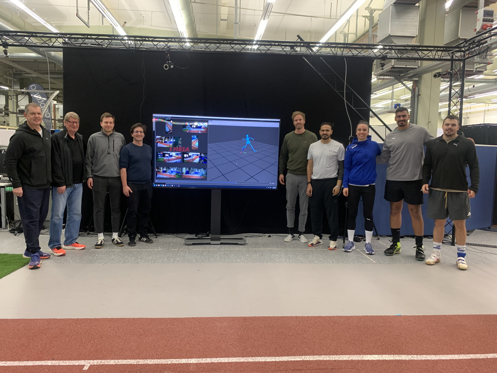 Gruppenfoto Menschen stehen rechts und links von einem Bildschirm