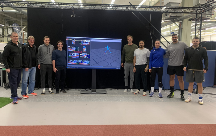 Gruppenfoto Menschen stehen rechts und links von einem Bildschirm