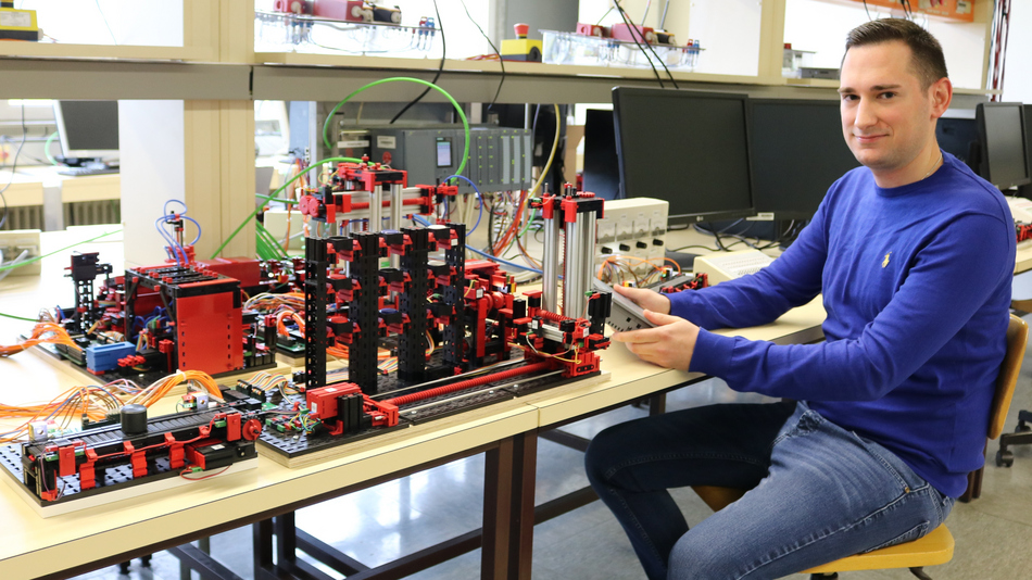 Laborleiter im Automatisierungslabor vor den Geräten sitzend