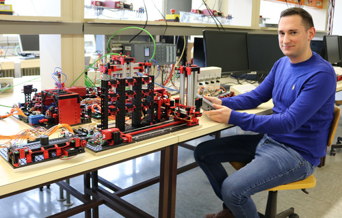 Laborleiter im Automatisierungslabor vor den Geräten sitzend