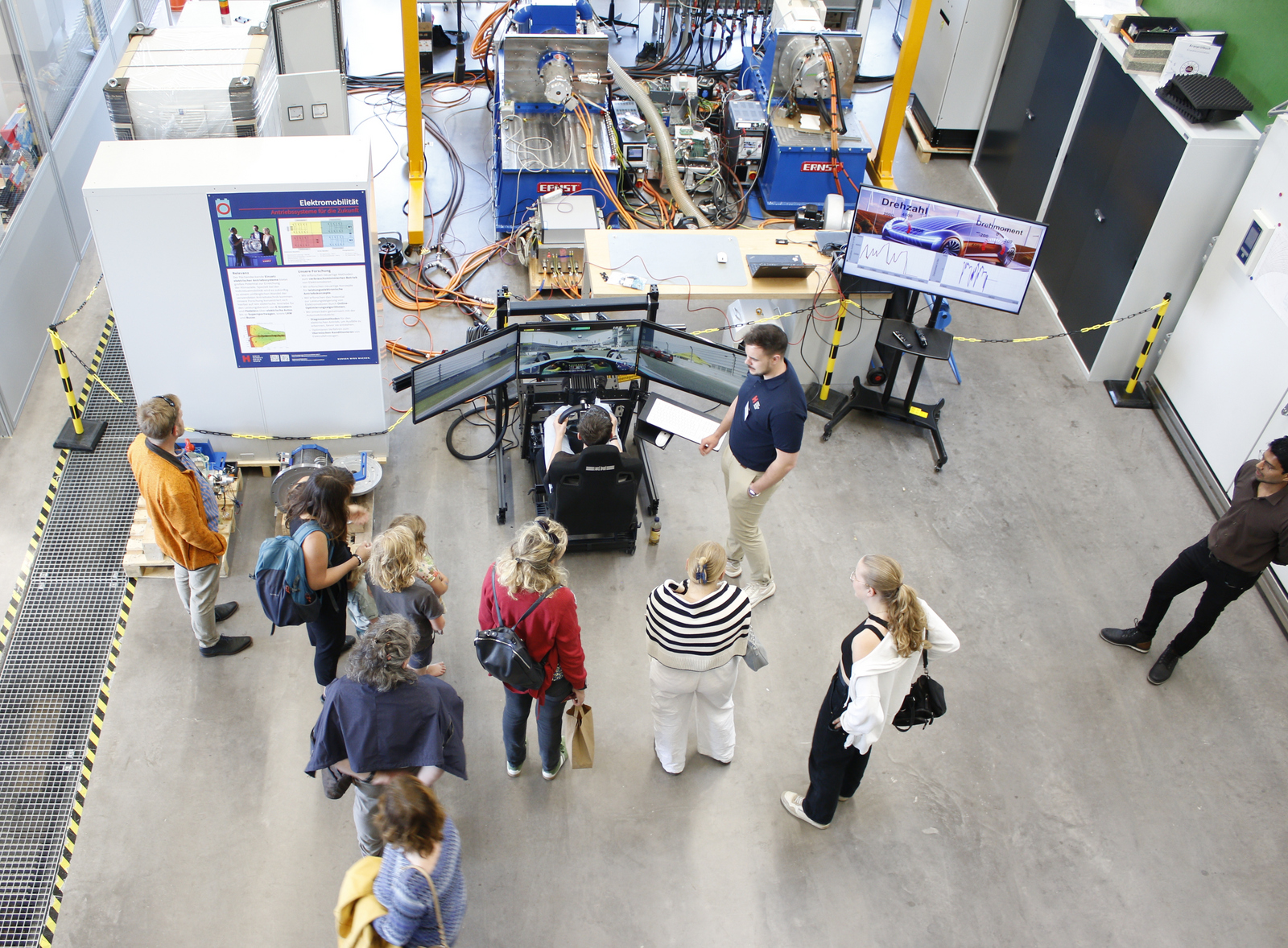 Blick von oben auf Menschen im und um den Fahrsimulator.