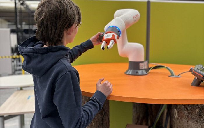 ein Junge interagiert mit einem Roboterarm