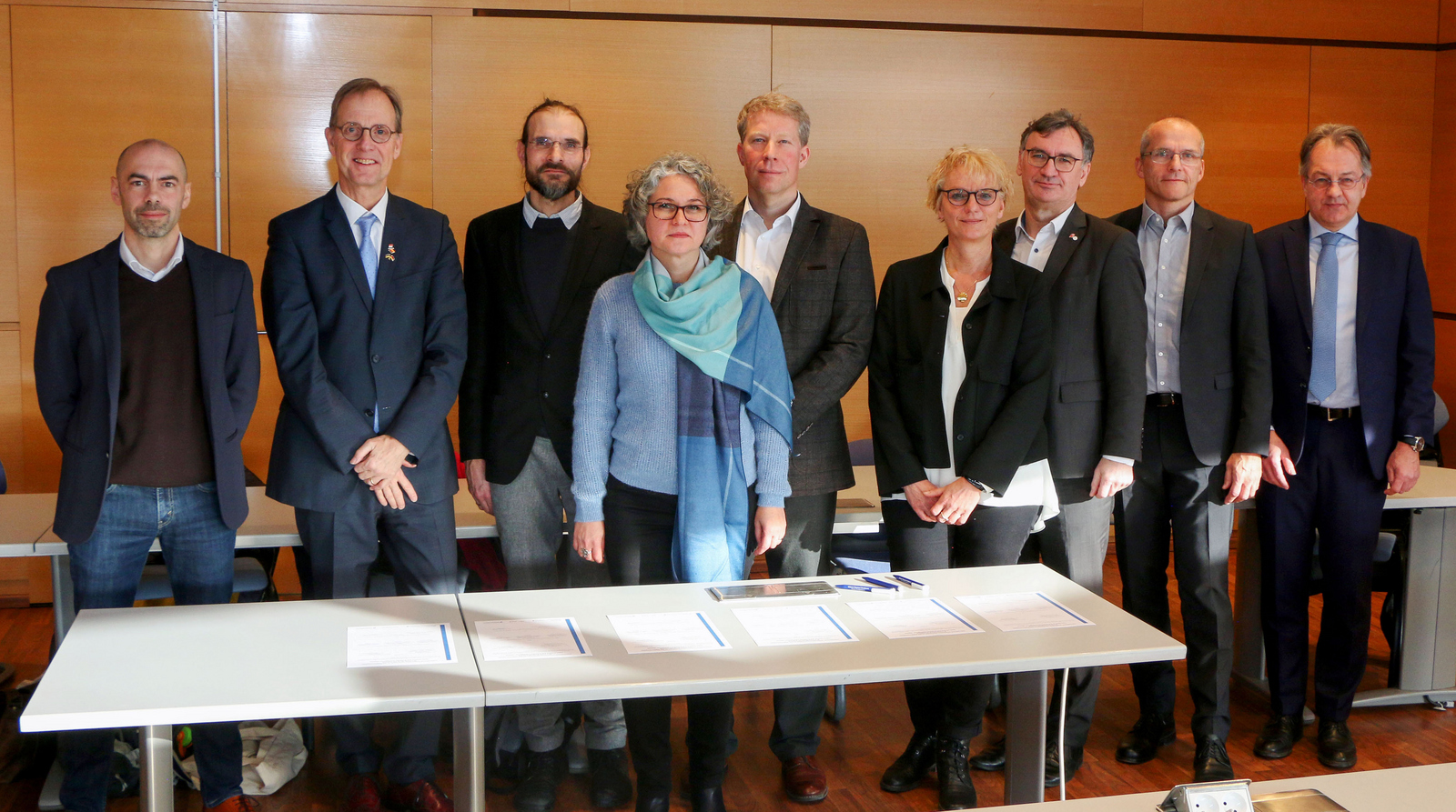 Die Vertreter der Hochschulen stehen hinter einem Tisch auf dem mehrere Ausfertigungen der Kooperationsvereinbarung zur Unterzeichnung bereit liegen.