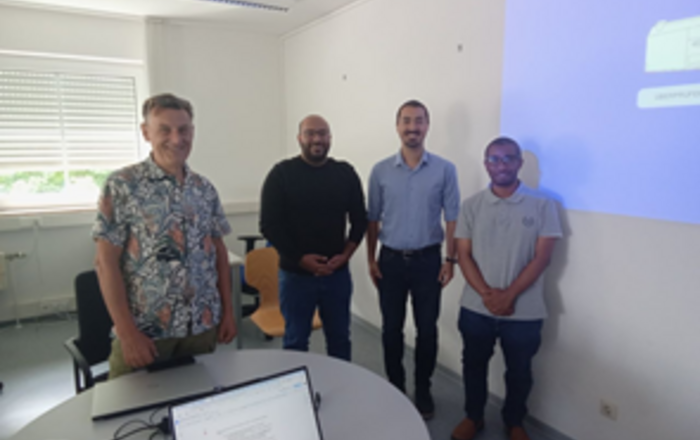 4 Personen stehen an einem Tisch nebeneinander