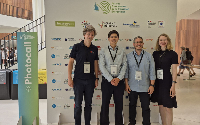 Drei Männer und eine Frau stehen vor einer Stellwand mit den Logos der Beteiligten der Energiewendekonferenz
