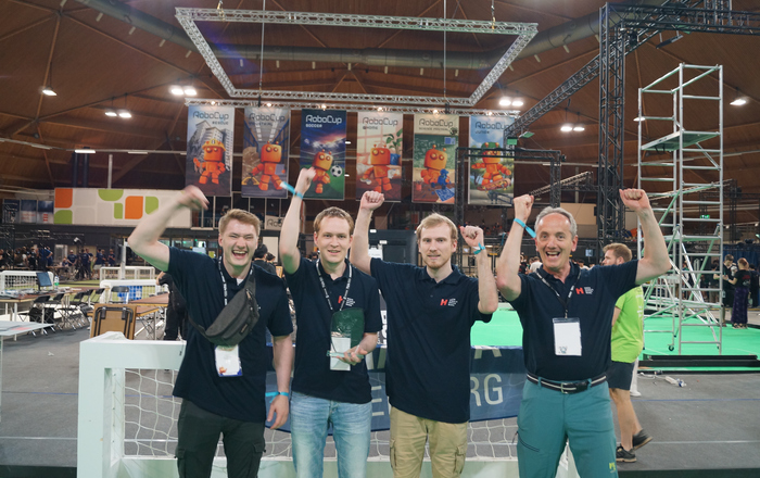 Drei Studierende und Prof. Dorer mit dem Pokal in Jubelpose