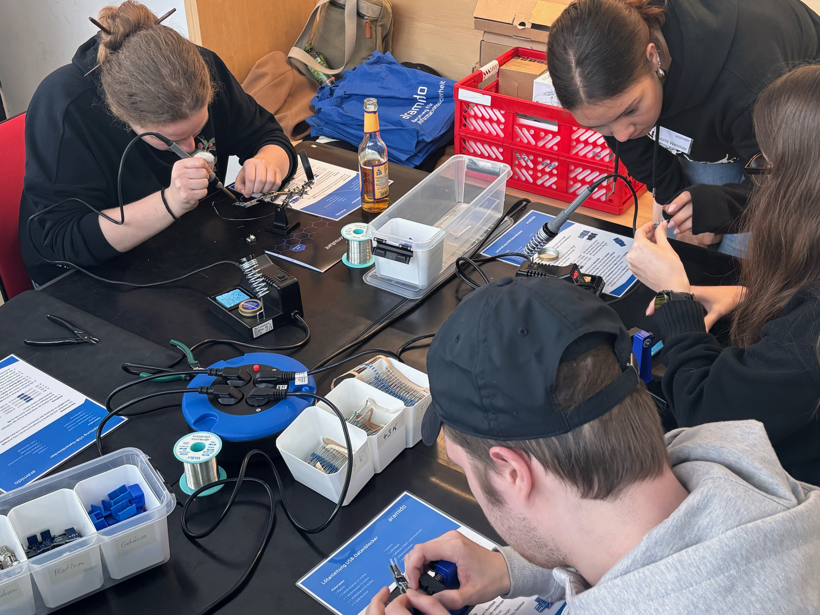 Junge Menschen sitzen an einem Tisch und löten USB-Blocker