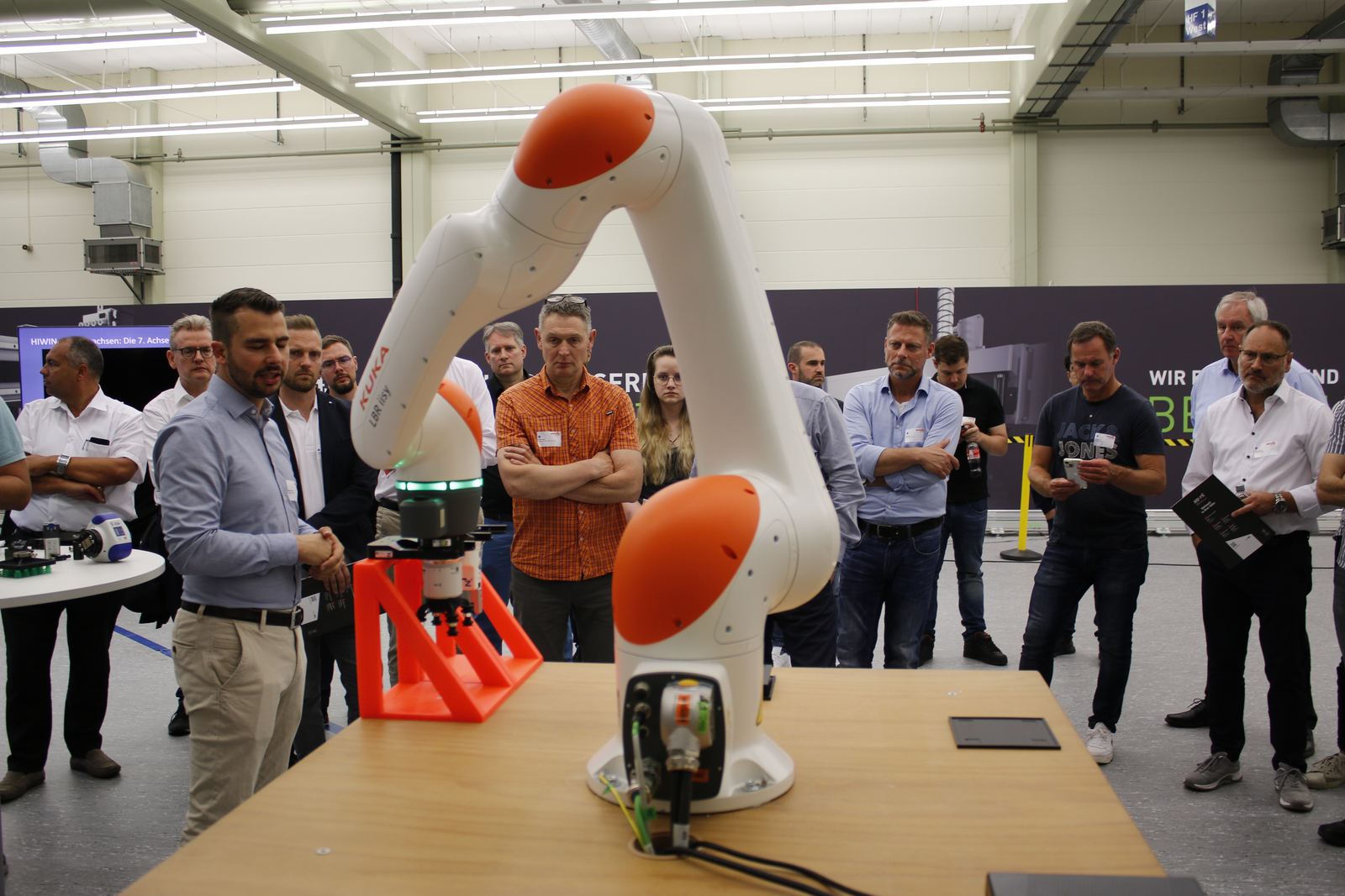 Zahlreichen Menschen stehen um einer Roboterarm herum