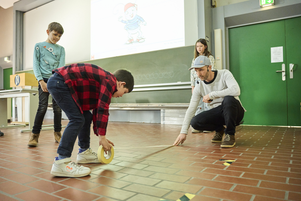 2025_Kinder-Uni_Klebeband_ausrollen