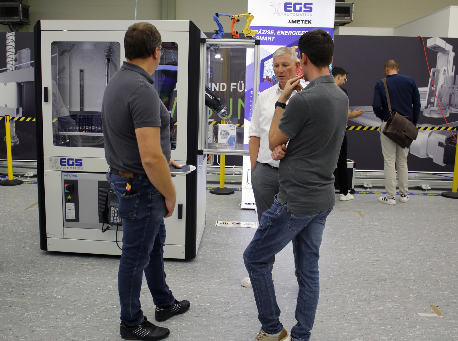 Drei Männer stehen vor einem Industrieroboter