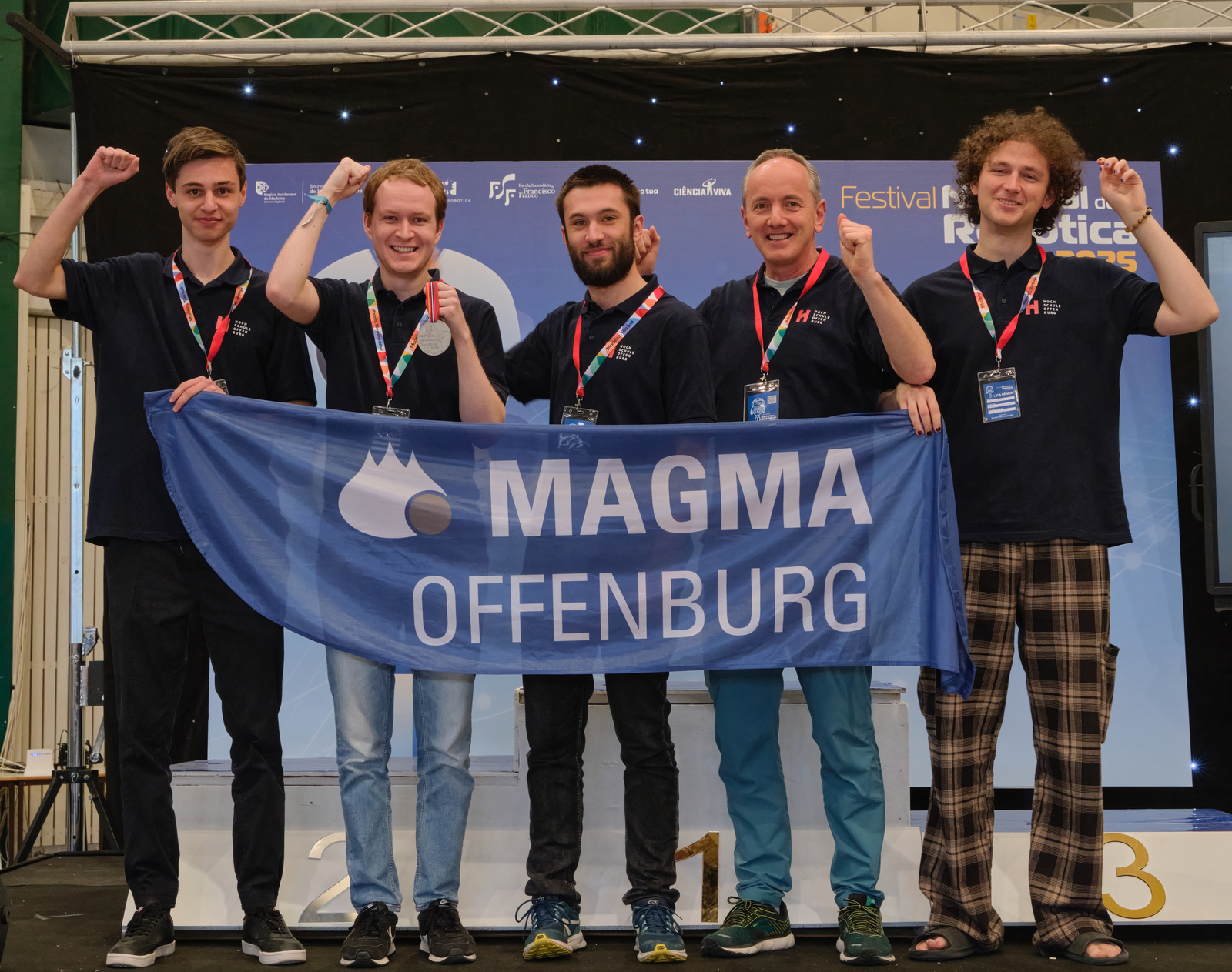 Foto des jubelnden Teams mit der Teamfahne