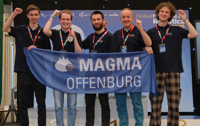 Foto des jubelnden Teams mit der Teamfahne