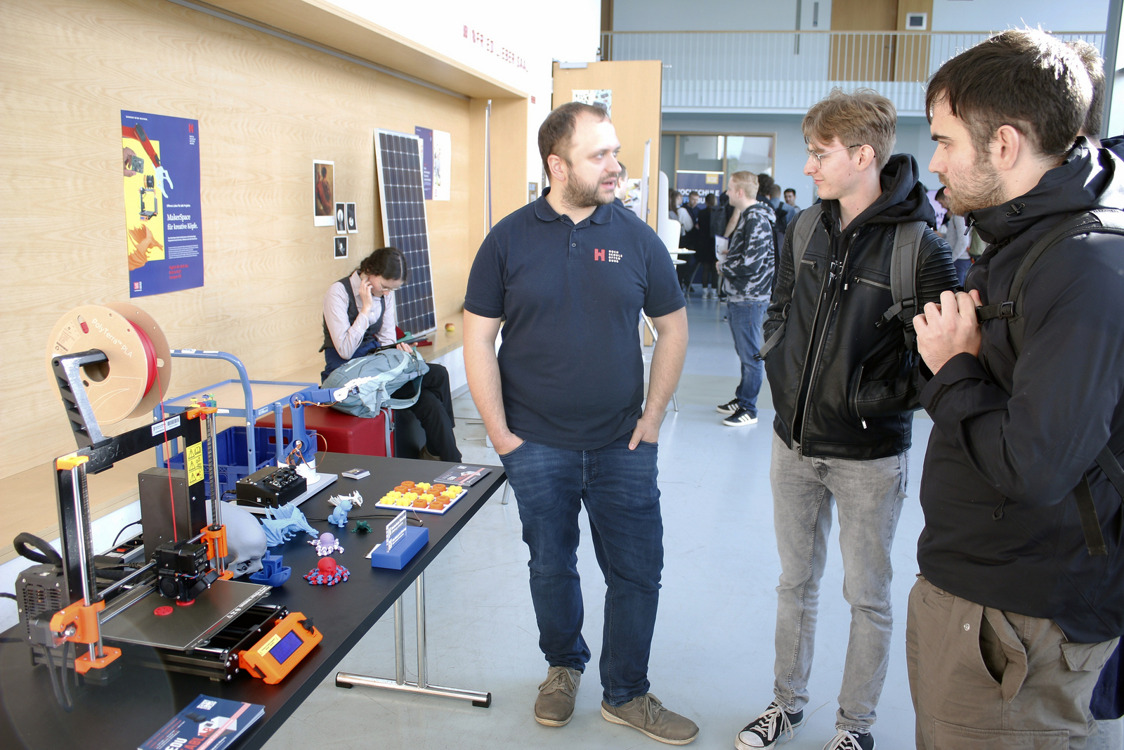 Mehrere junge Männere stehen vor einem Tisch auf dem ein kleiner 3D-Drucker steht. Drumherum sind mehrere ausgedruckte Gegenstände zu sehen