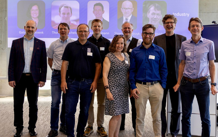 9 Peronen vor einer Leinwand