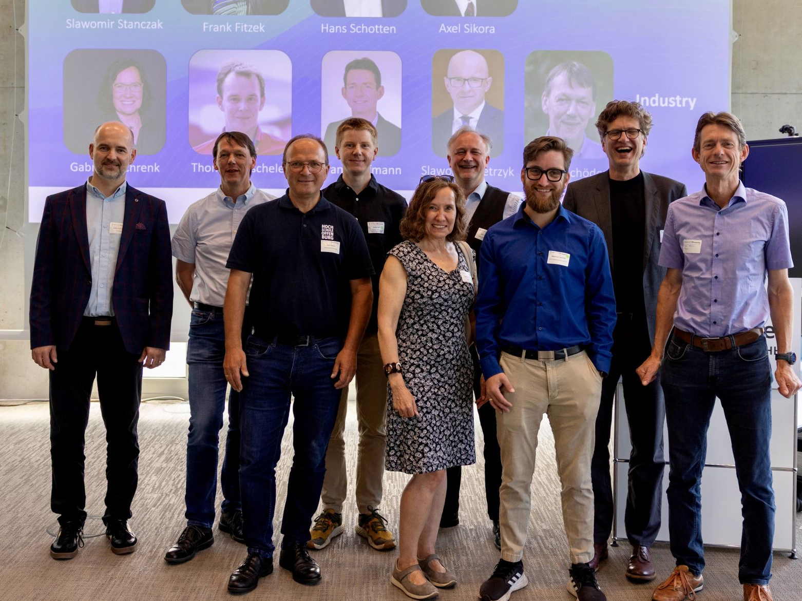 9 Peronen vor einer Leinwand