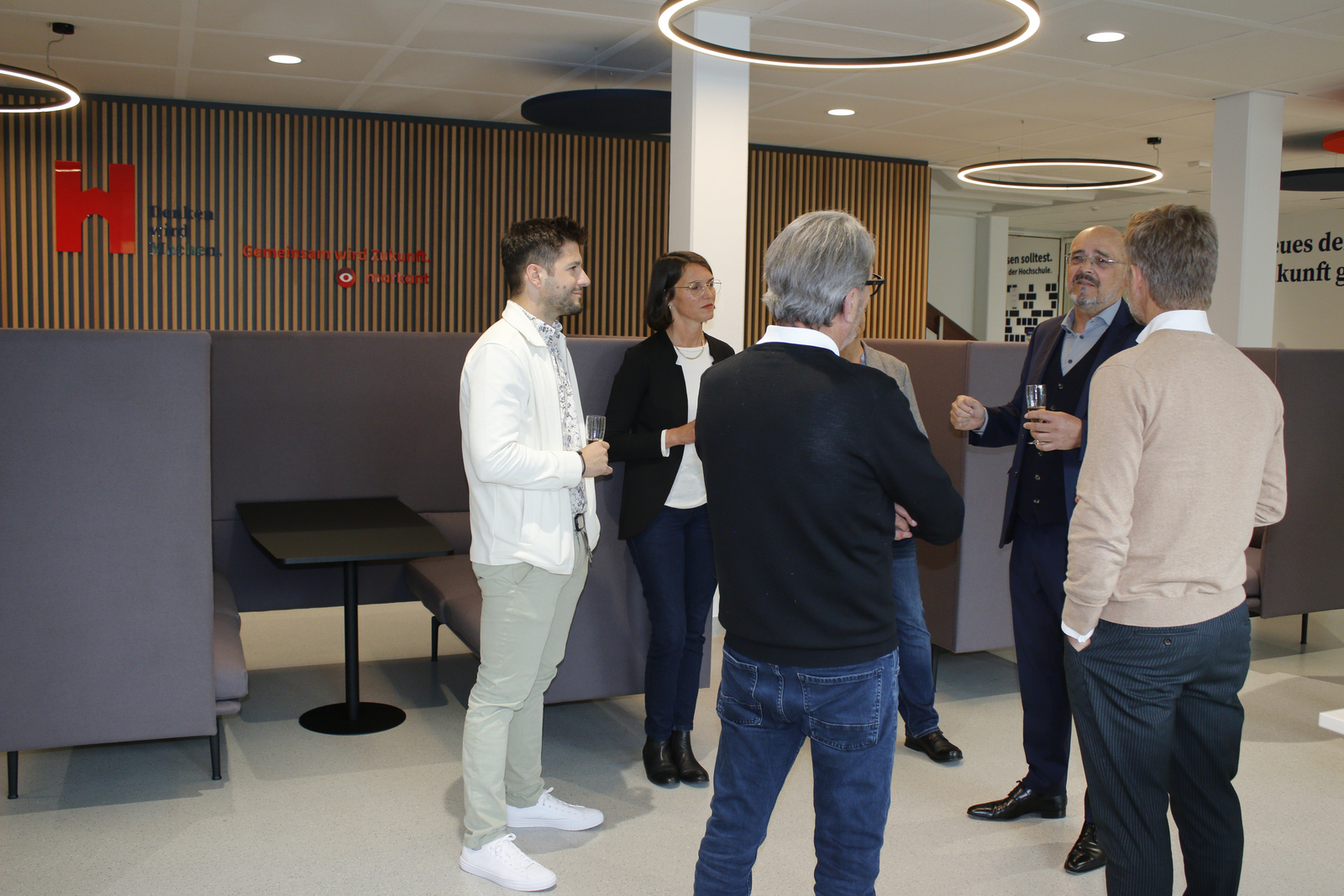 Eine Gruppe steht vor Sofalounges und unterhält sich