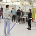 Eine Gruppe von Studenten in einem Labor mit Roboterarmen im Hintergrund