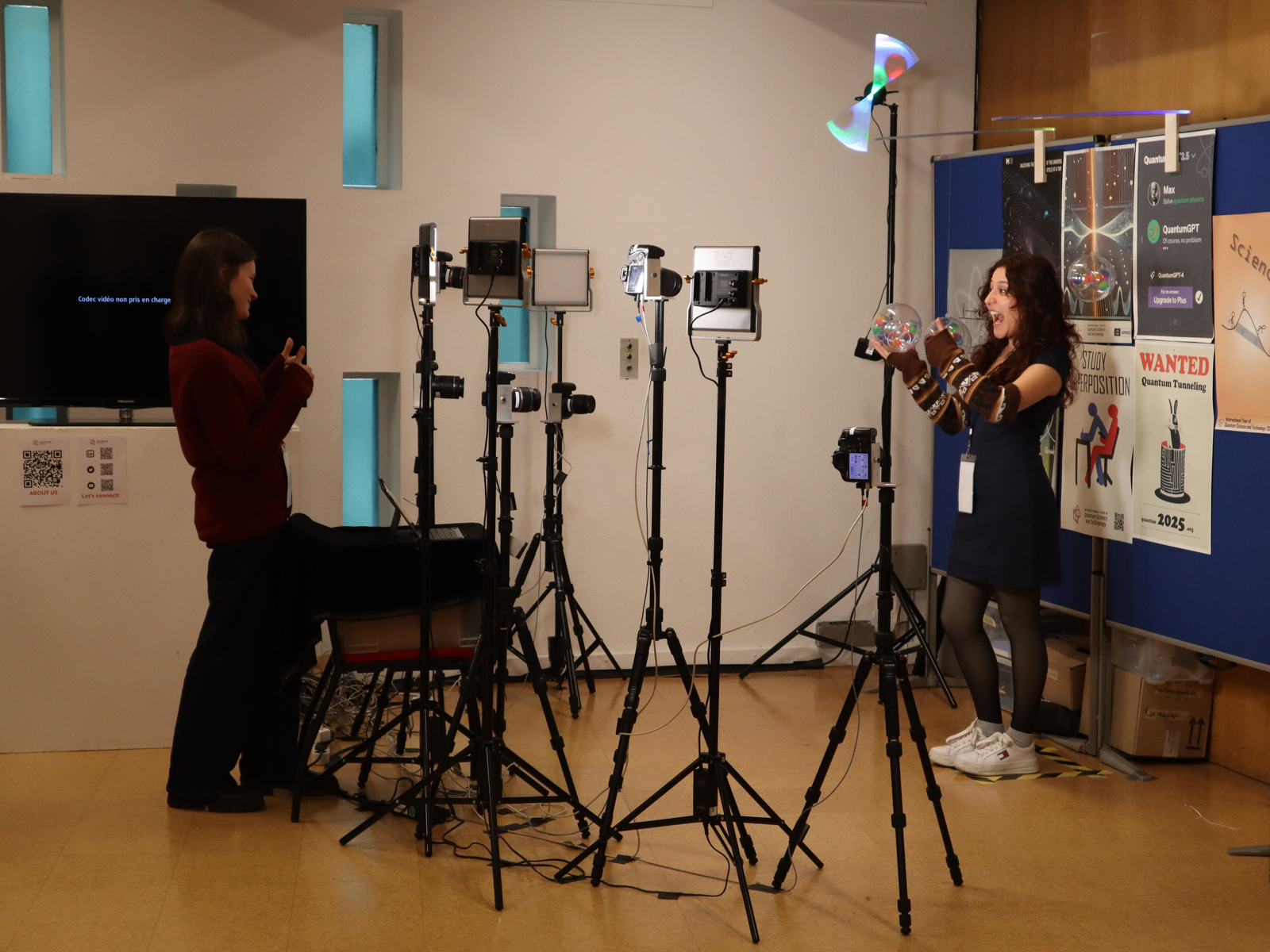 Eine junge Frau stellt Kameras um eine andere junge Frau, die eine Kugel in der Hand hält, herum auf