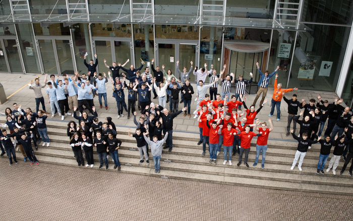 Alle Beteiligten jubelnd auf der Treppe von Gebäude D von oben mit einer Drohne aufgenommen 