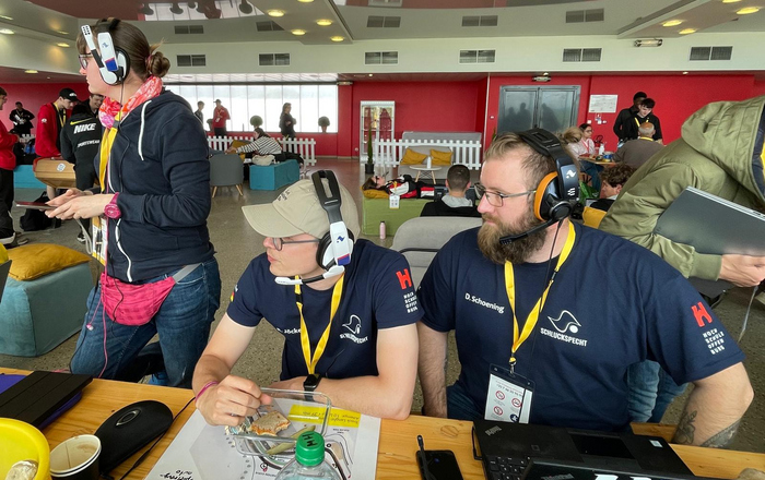Drei Teammitglieder sitzen vor an Tisch mit Laptops