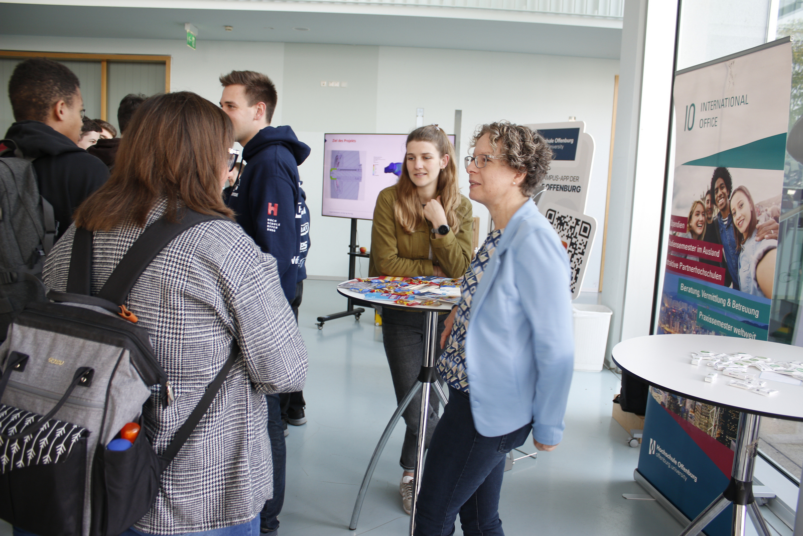 Eine Frau informiert sich am Tisch des International Center bei zwei anderen Frauen