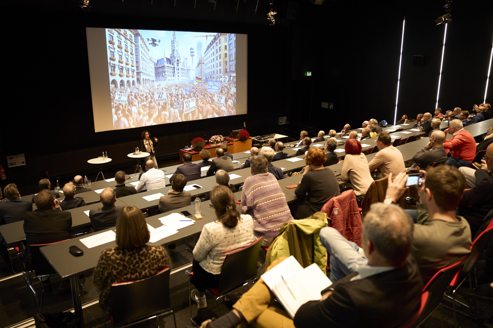Blick über die Gäste hinweg zum Rednerpult und die Leinwand dahinter