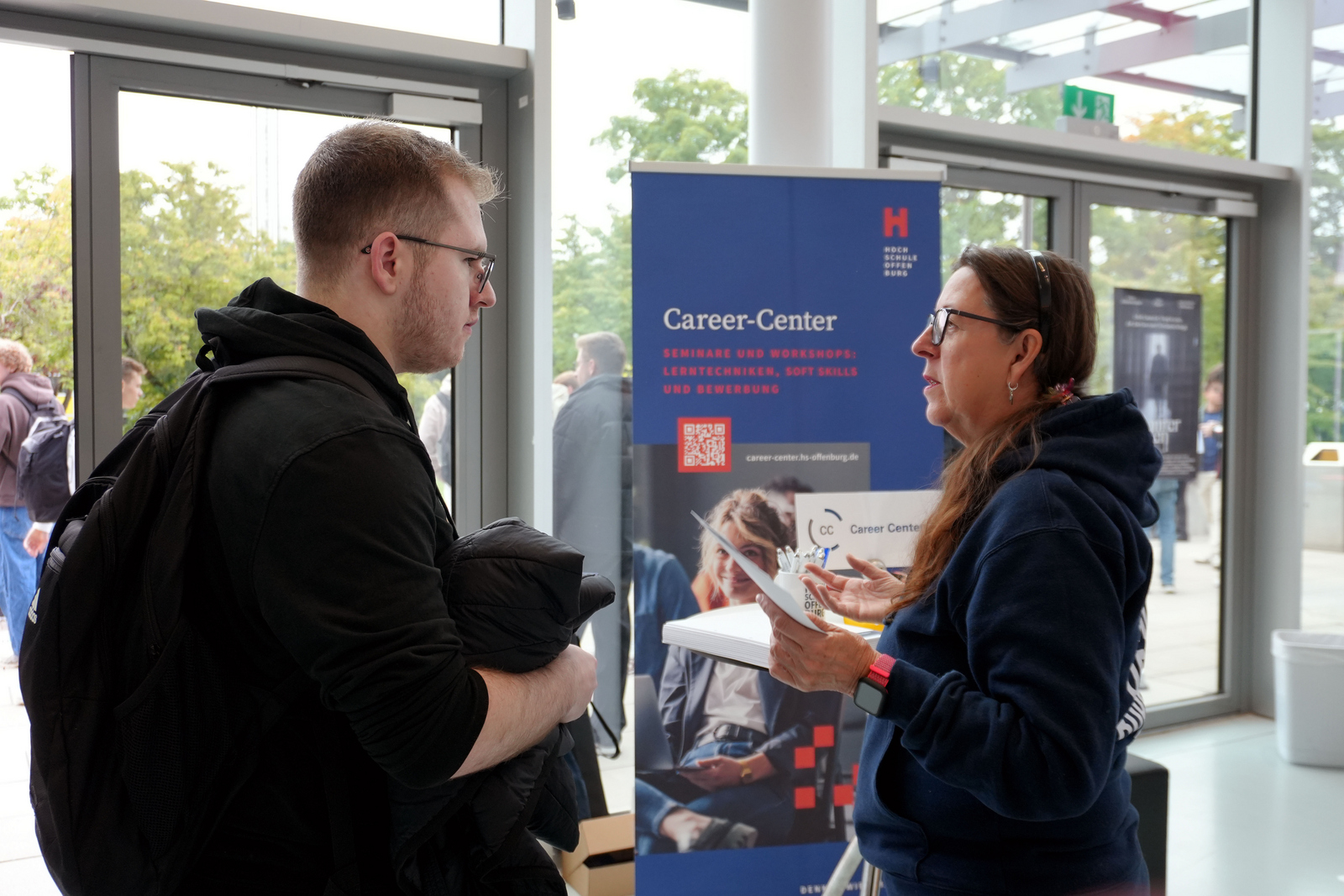 Ein Mann und eine Frau stehen vor eine Roll-up und unterhalten sich 