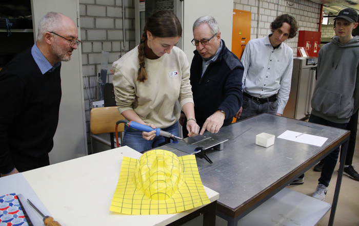 Eine Schülerin versucht sich unter Anleitung der Professoren sowie den Blicken ihres Lehrers und eines Mitschülers beim Thermoschweißen.