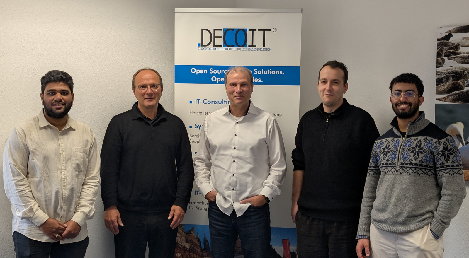 5 Personen nebeneinander vor einem DECOIT RollUp