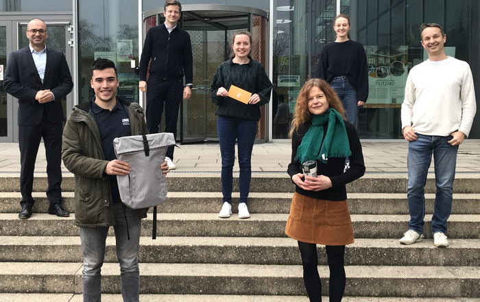 Kanzler Bülent Tarkan, Gewinner René Behmann, der stellvertretende Nachhaltigkeitsbeauftragte Niklas Hartmann, die Zweit- und Drittplatzierten Kathrin Grusa und Simone Schede, Jana Gebhardt von der AG Nachhaltigkeit und der Nachhaltigkeitsbeauftragte Daniel Kray stehen vor dem D-Gebäude.