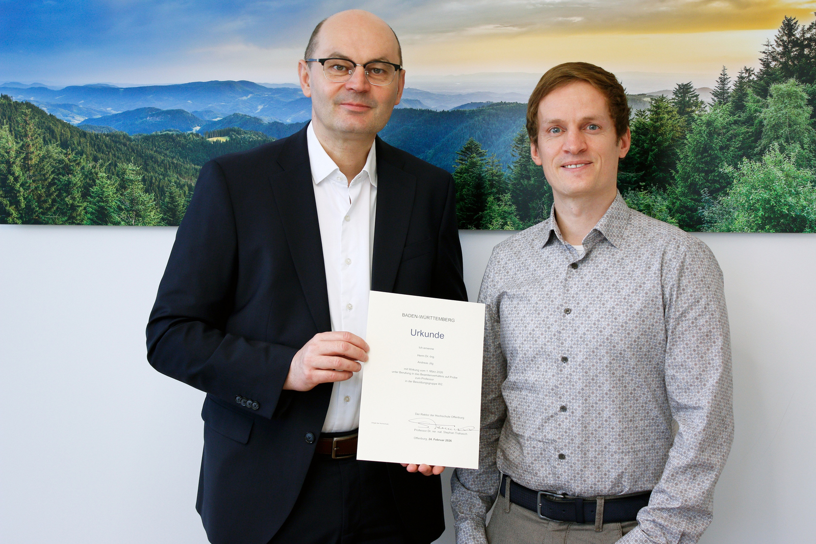 Zwei Männer stehen vor einem Schwarzwaldfoto und halten ein Urkunde 