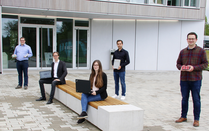 Prof. Dr. Wolfang Bessler und die Doktorandin Jennifer Brucker (sitzend von links) sowie die Doktoranden Michael Quarti, David Schmider und Jonas Braun (stehend von links) vor dem RIZ Energie.
