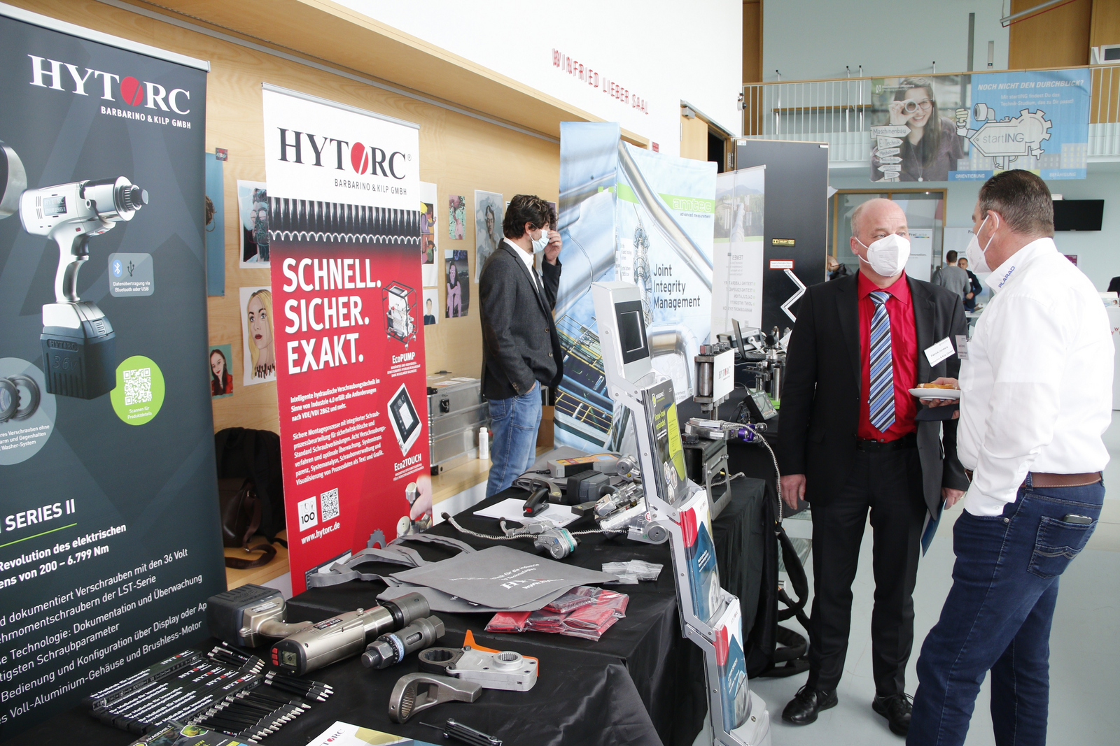 Teilnehmende der 2. Schraubenfachtagung tauschen sich an einem Firmenstand aus.