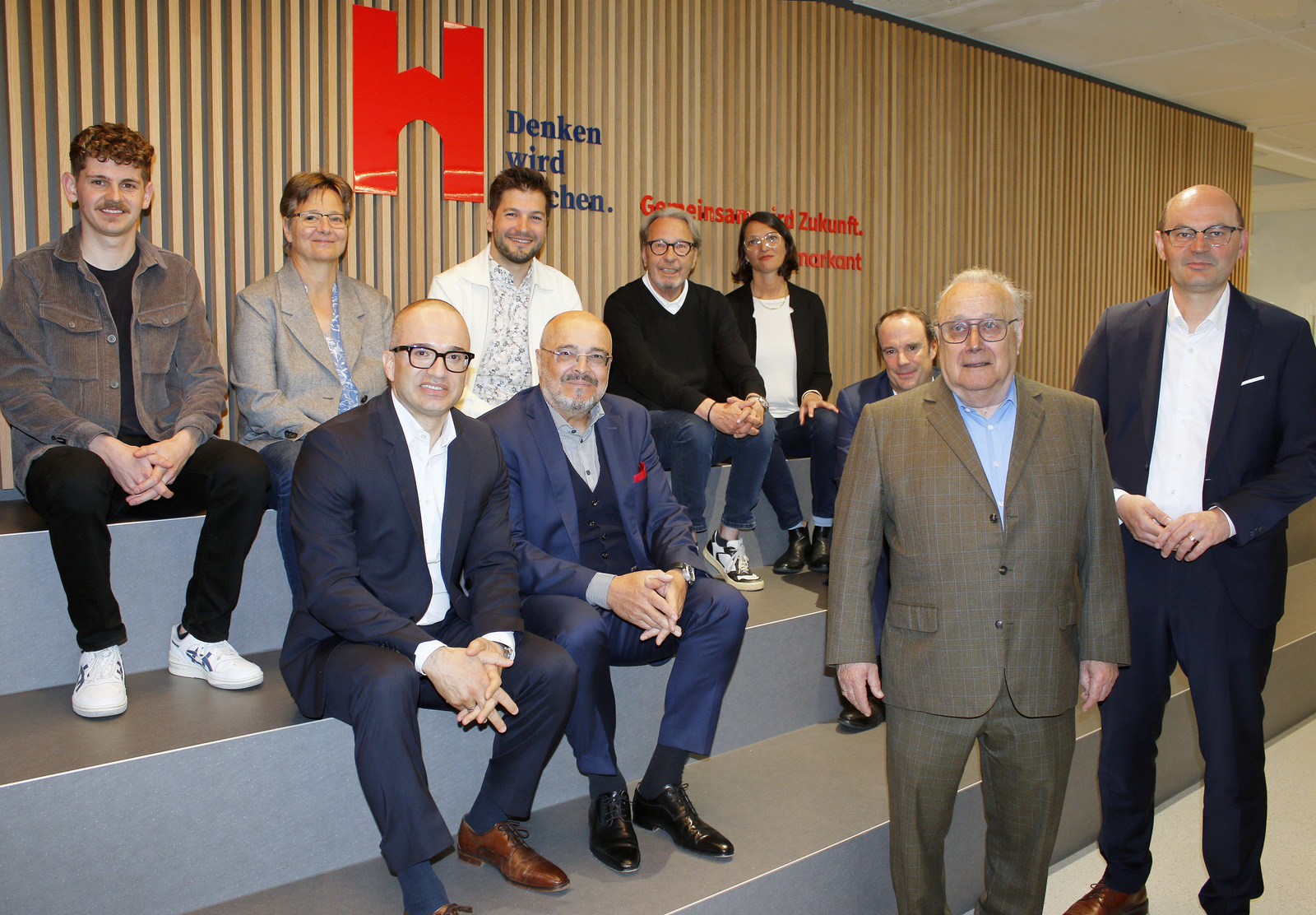 Gruppenfoto der Beteiligten auf der neuen spanischen Treppe in Holzlamellenoptik sitzend beziehungsweise davor stehend