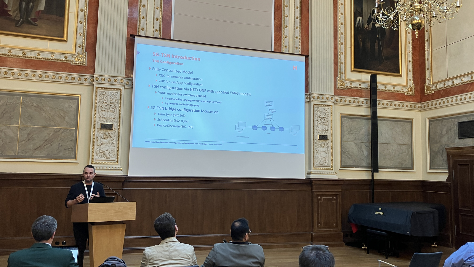 1 person am Rednerpult, Leinwand im Hintergrund