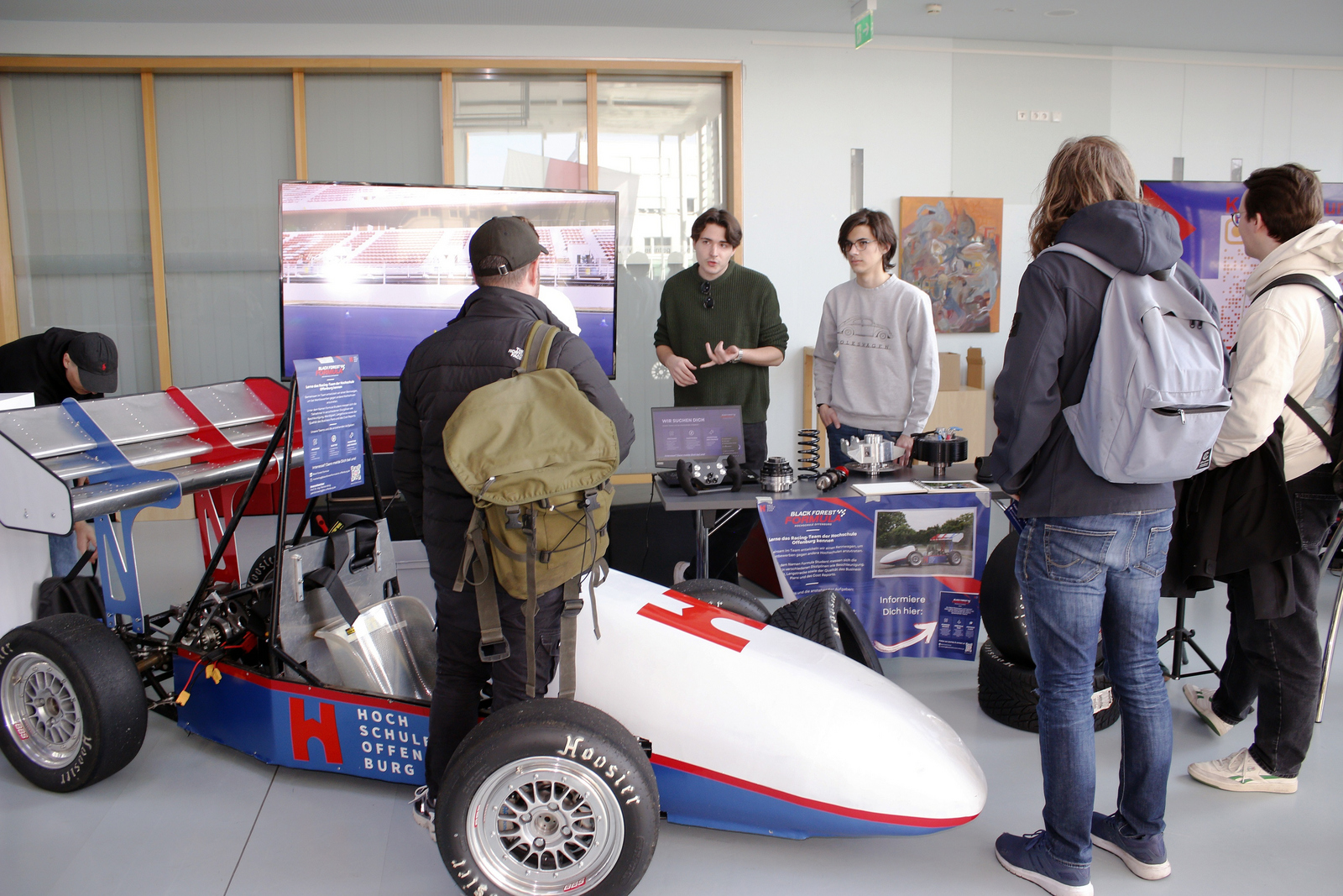 Junge Leute stehen um elektrischen Rennwagen herum
