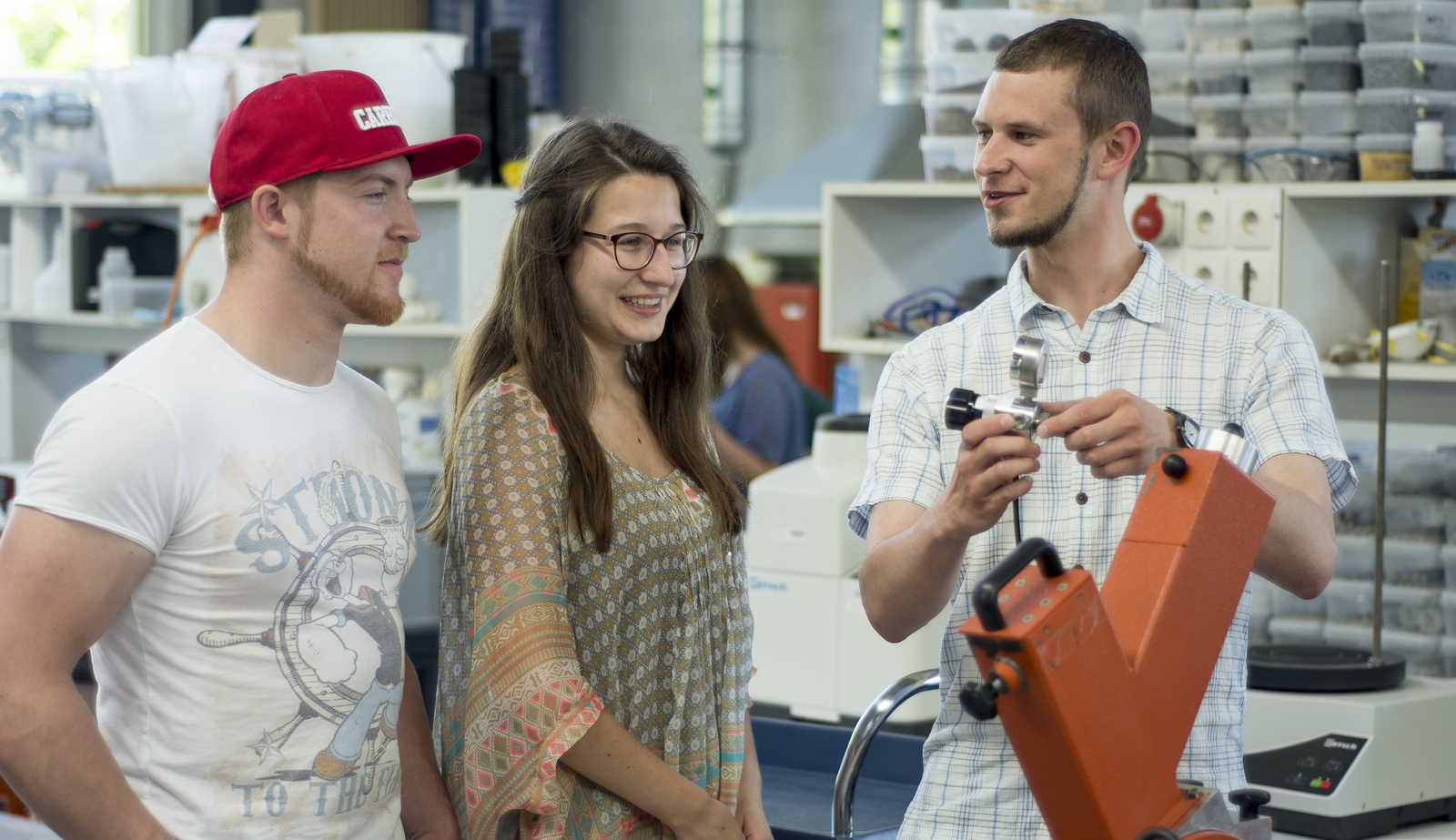 Zwei junge Männer und eine Frau an einer Maschine