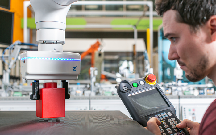 Student programmiert Roboterarm, der Klötzchen bewegt