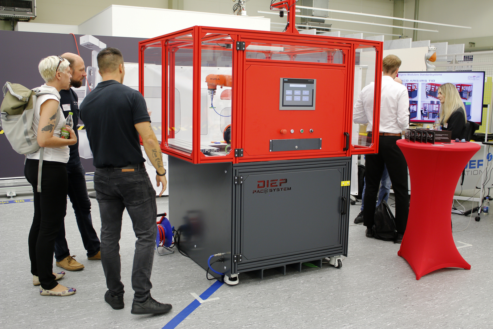 Menschen stehen um einen roten Industrieroboter herum
