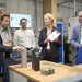 Die Personen im Batterielabor auf einem Tisch stehen Batterien, die Ministerin hält eine in der Hand